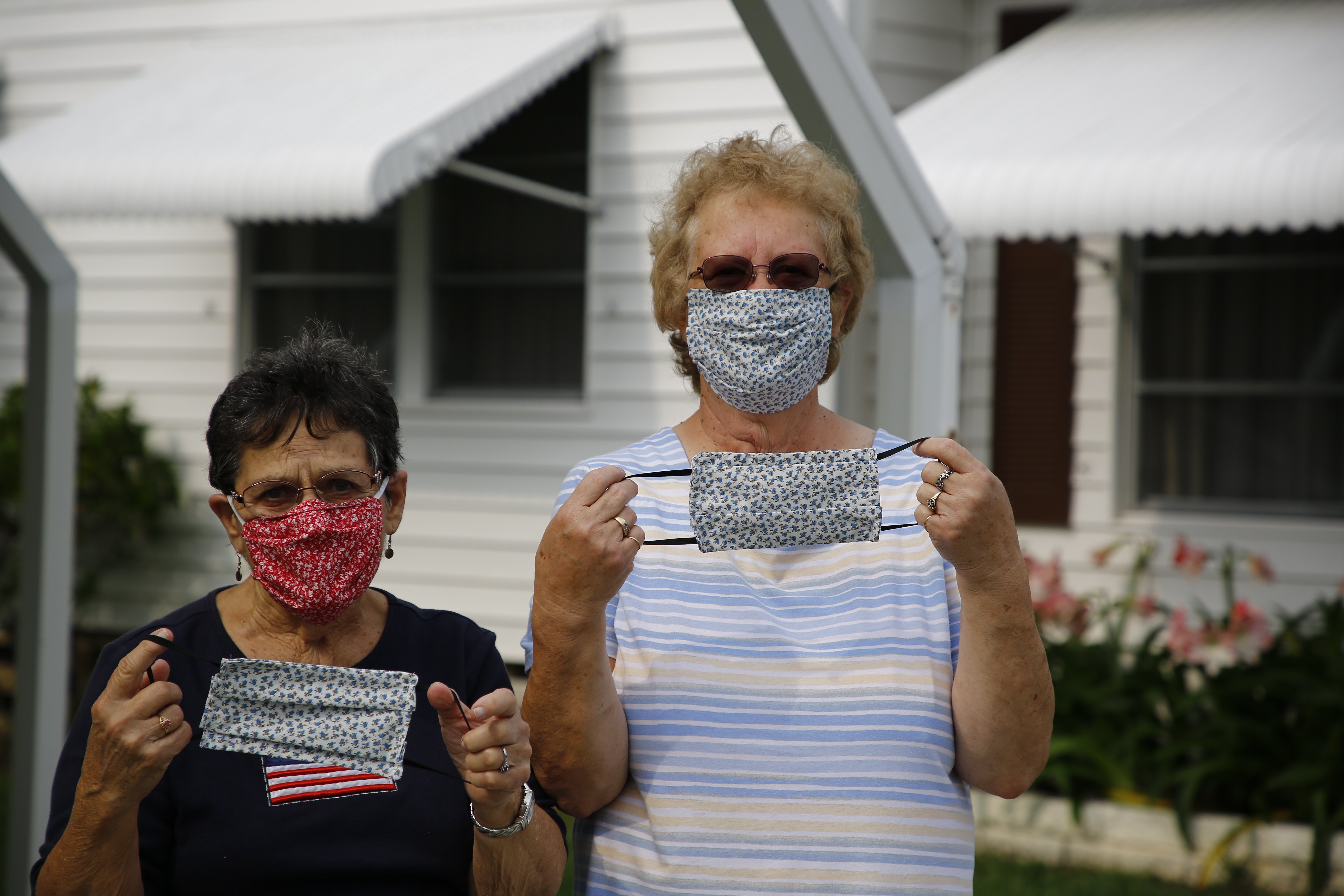 Delores Johnson and Marilyn Gleason pose for a portrait with their hand sewn masks in front of their Palm Hill Country Club home on April 10, 2020 in Largo, Florida. The women started making masks to help protect their neighbors after two people died in the community because of COVID-19.