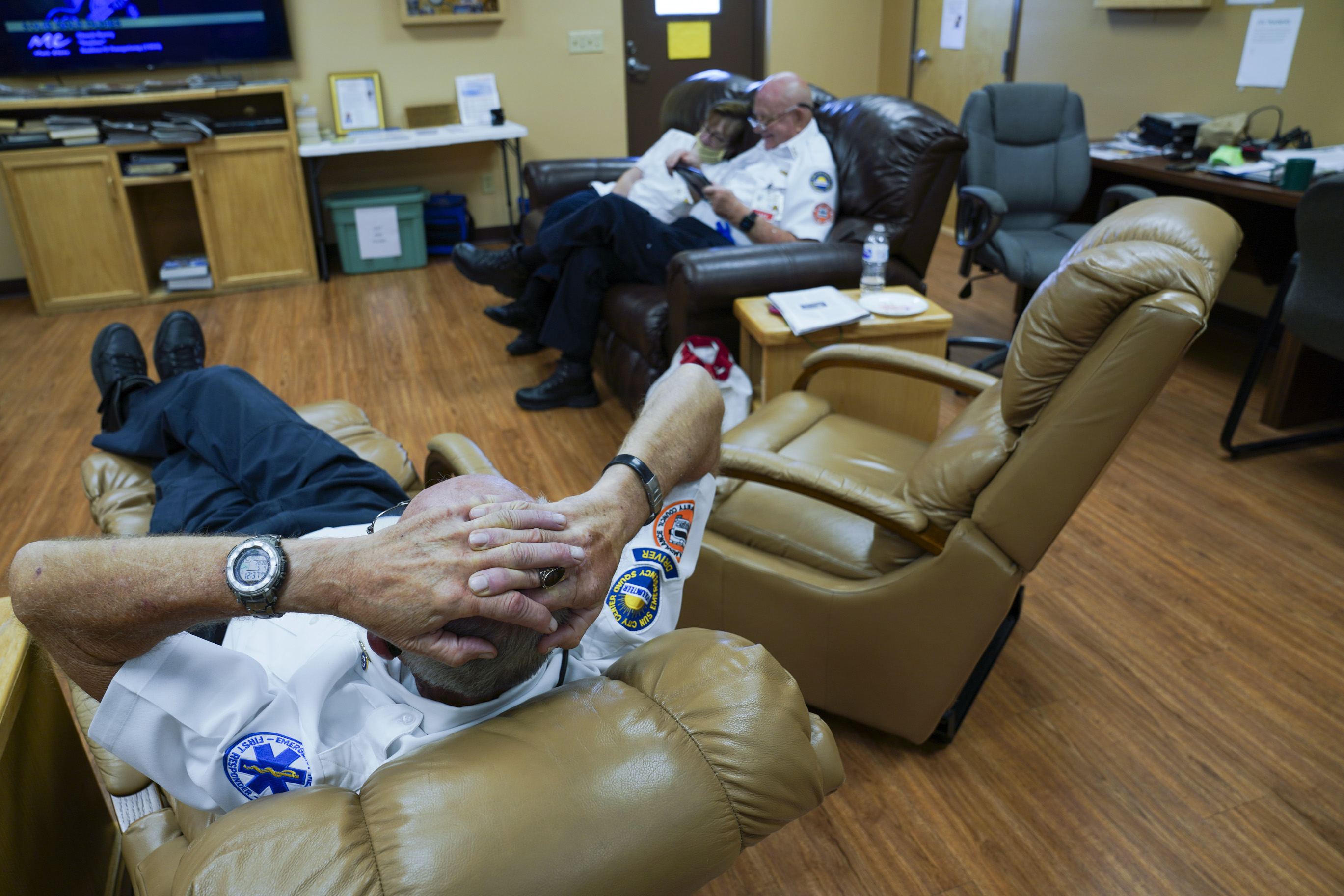 After lunch there's a break in calls and Kent Marchuck, 67, stretches out to rest on an armchair while married couple, Helen Corrady, 67, and Tom Canady, 76, browse their tablets, at the Sun City Center Emergency Squad Station on May 4, 2020 in Sun City Center.