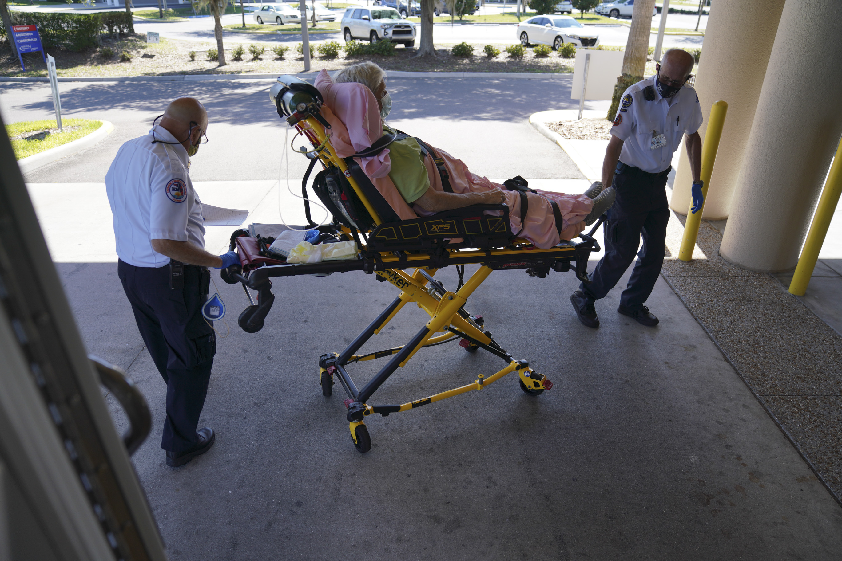 Tom Canady, 76, and Kent Marchuck, 67, with the Sun City Center Emergency Squad, wheel an 86-year-old, male patient into the emergency room after picking him up for dizziness, on May 4, 2020 in Sun City Center.