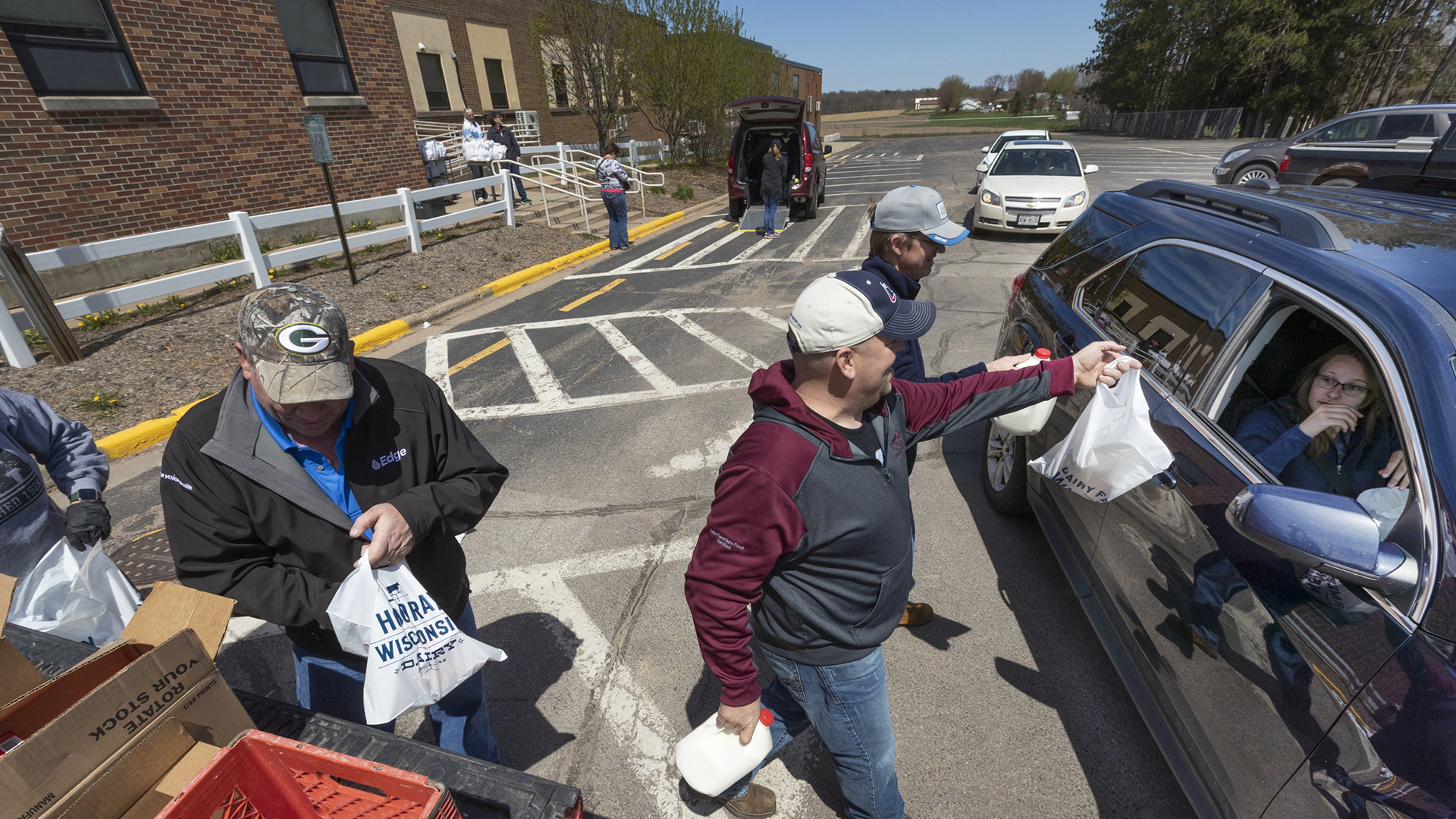 Future Farmers of America Alumni including Dennis Roehl, left, Adam Luchterhand and Tom Odeen hand out free food Thursday, May 7, 2020 outside the public schools in Loyal, Wis.
