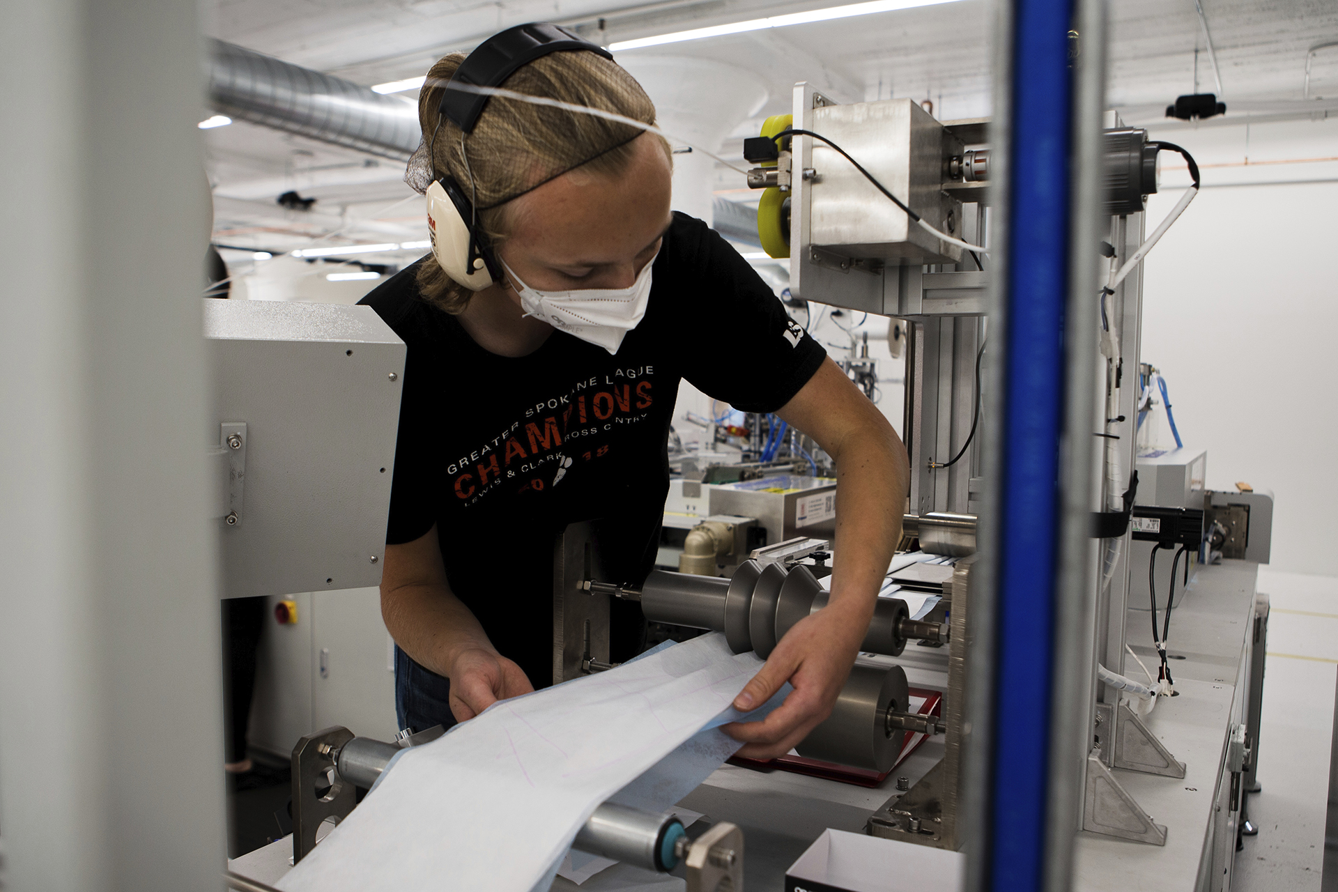 In this undated photo provided by Outdoor Research in September 2020, a worker adjusts material on a machine that makes surgical masks in Seattle. As the city became a major coronavirus hotspot, the clothing and sportswear company also switched gears.