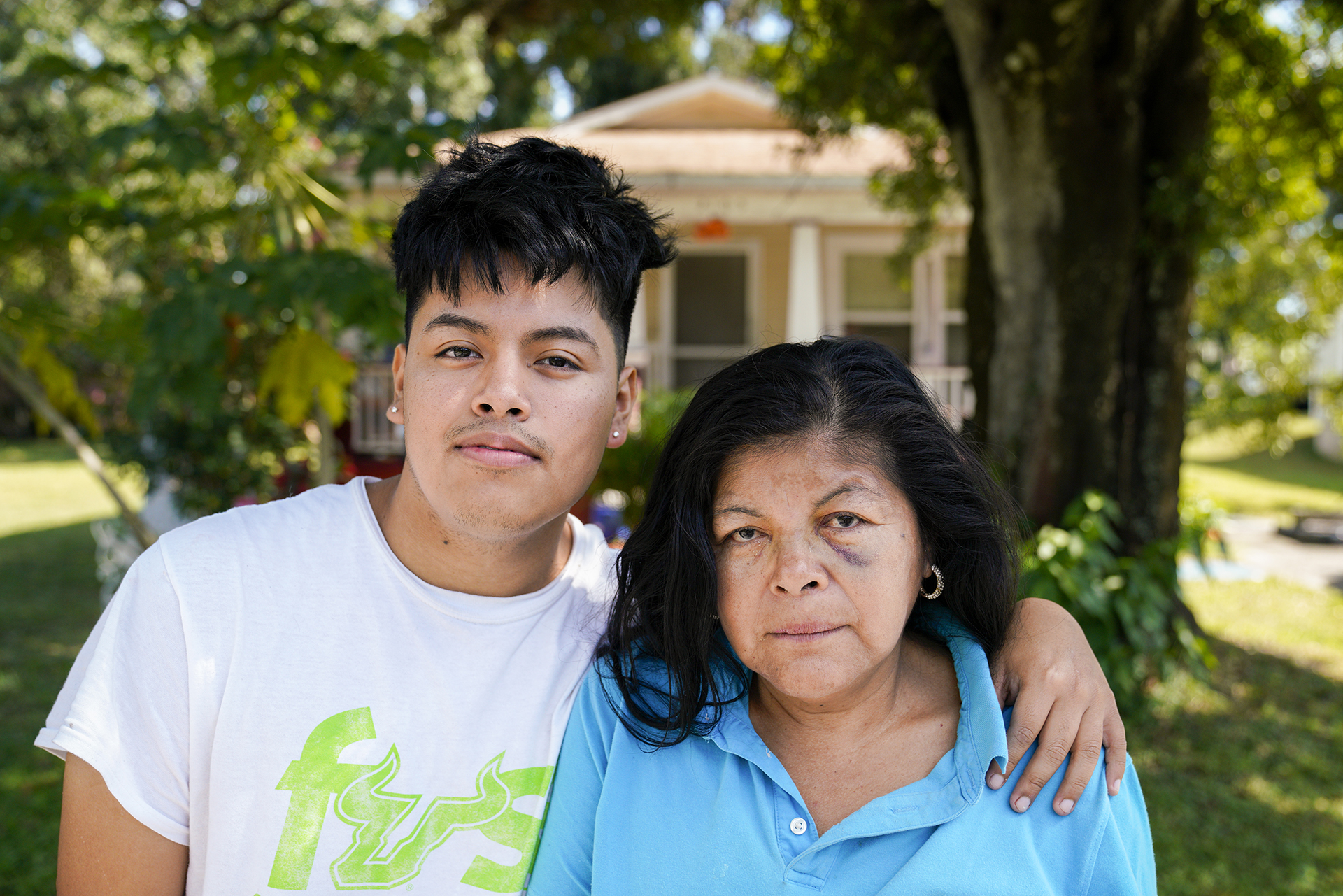 Josefina Zepeda, 56, and her son, Gustavo Araujo, 21, pose for a portrait in front of their home which neighbors the Gopher Resource lead smelter. Zepada says her son developed asthma since they moved to the property and recently his condition has worsened, Monday, Nov. 1, 2021 in Tampa.