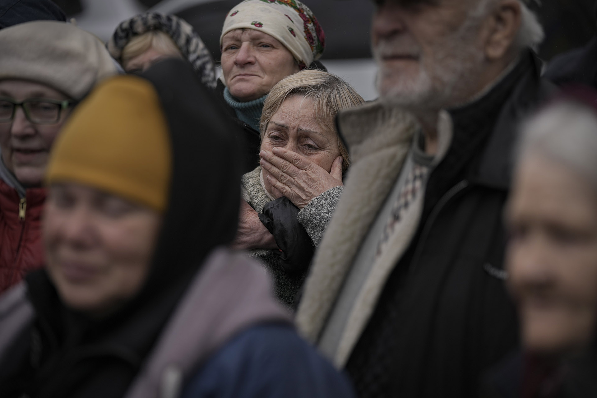 FILE - A woman cries as residents listen to a Ukrainian serviceman speaking after a convoy of military and aid vehicles arrived in the formerly Russian-occupied Kyiv suburb of Bucha, Ukraine, April 2, 2022.