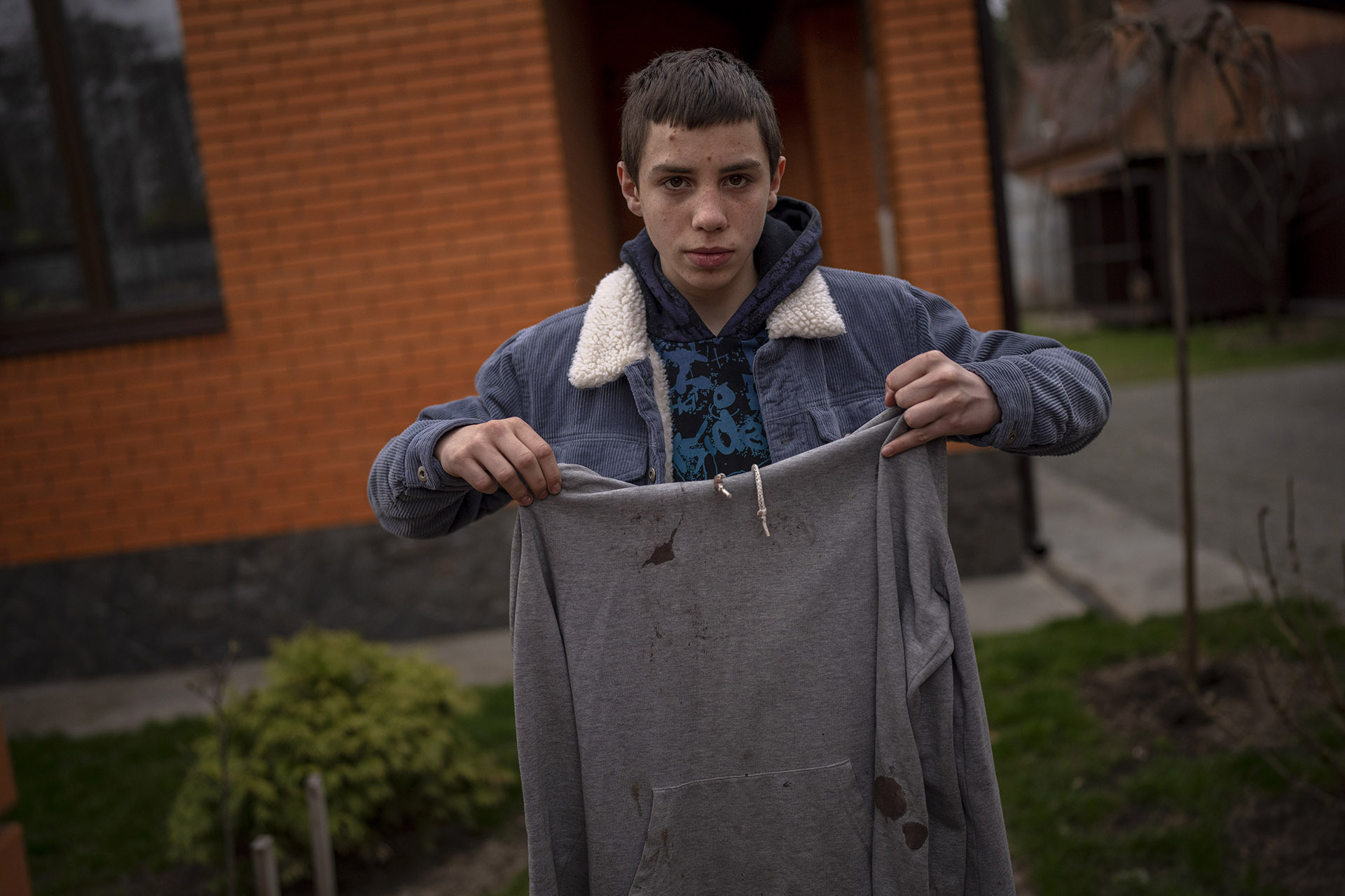 On April 19, 2022, Yura Nechyporenko, 15, holds the hoodie he was wearing the day he says a Russian soldier tried to execute him in Bucha, on the outskirts of Kyiv, Ukraine. His father was killed in the same incident. The hoodie, bloodied at the elbow where a bullet had pierced him, is now the centerpiece of the family’s search for justice.