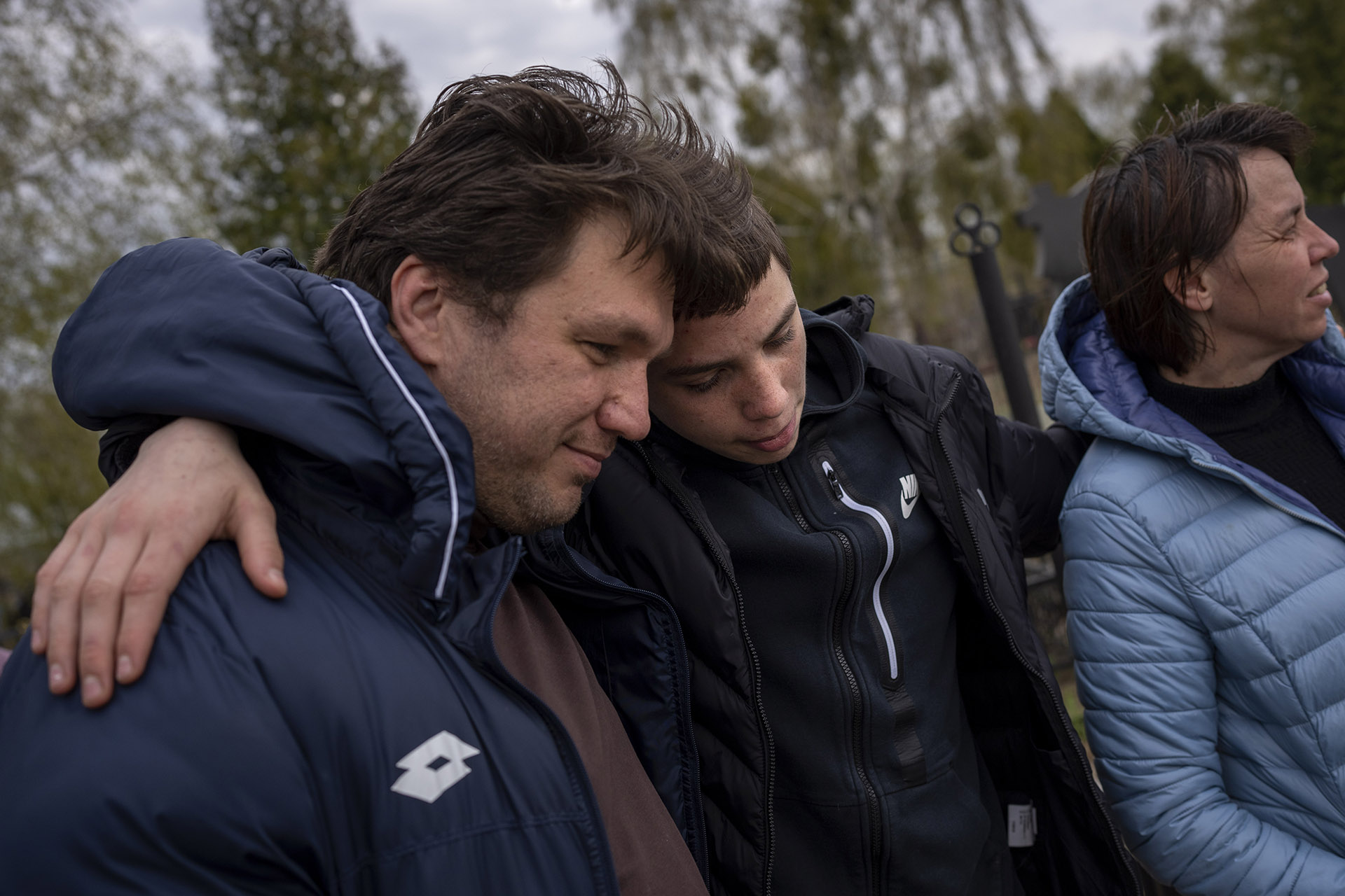 Yura Nechyporenko, 15, hugs his uncle Andriy Nechyporenko next to the grave of his father, Ruslan Nechyporenko, at a cemetery in Bucha, on the outskirts of Kyiv, Ukraine, on Monday, April 25, 2022.