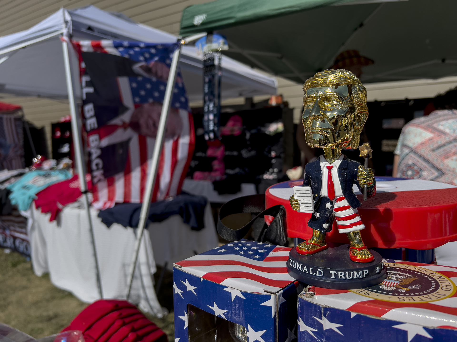 A golden bobblehead of former President Donald Trump and other merchandise is displayed for sale during the ReAwaken America tour at Cornerstone Church in Batavia, N.Y., Saturday, Aug. 13, 2022. (AP Photo/Carolyn Kaster)