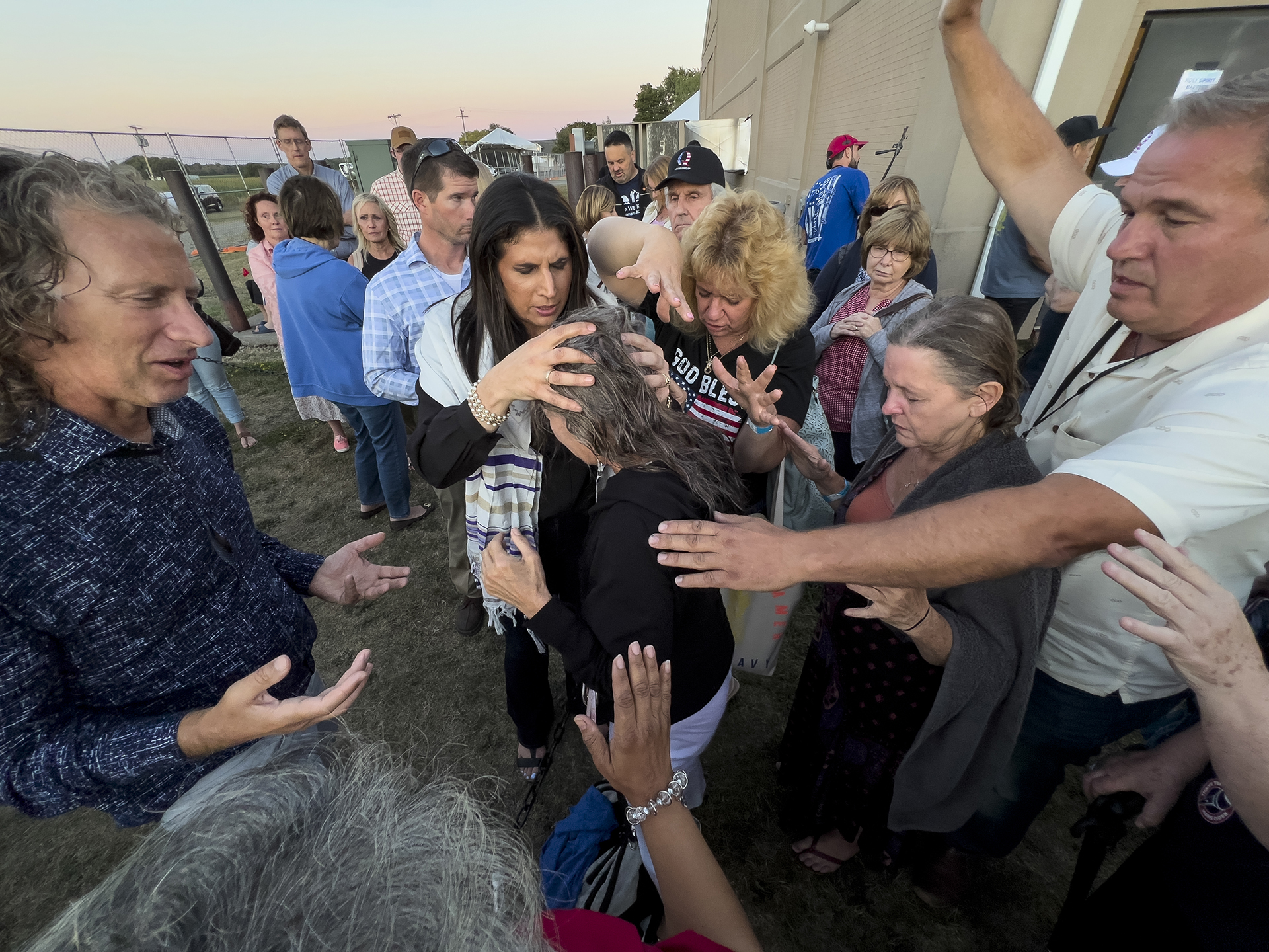 Amanda Grace of Ark of Grace Ministries and a group of people gather in prayer around a woman for the laying of hands during the ReAwaken America tour at Cornerstone Church in Batavia, N.Y., Friday, Aug. 12, 2022. (AP Photo/Carolyn Kaster)