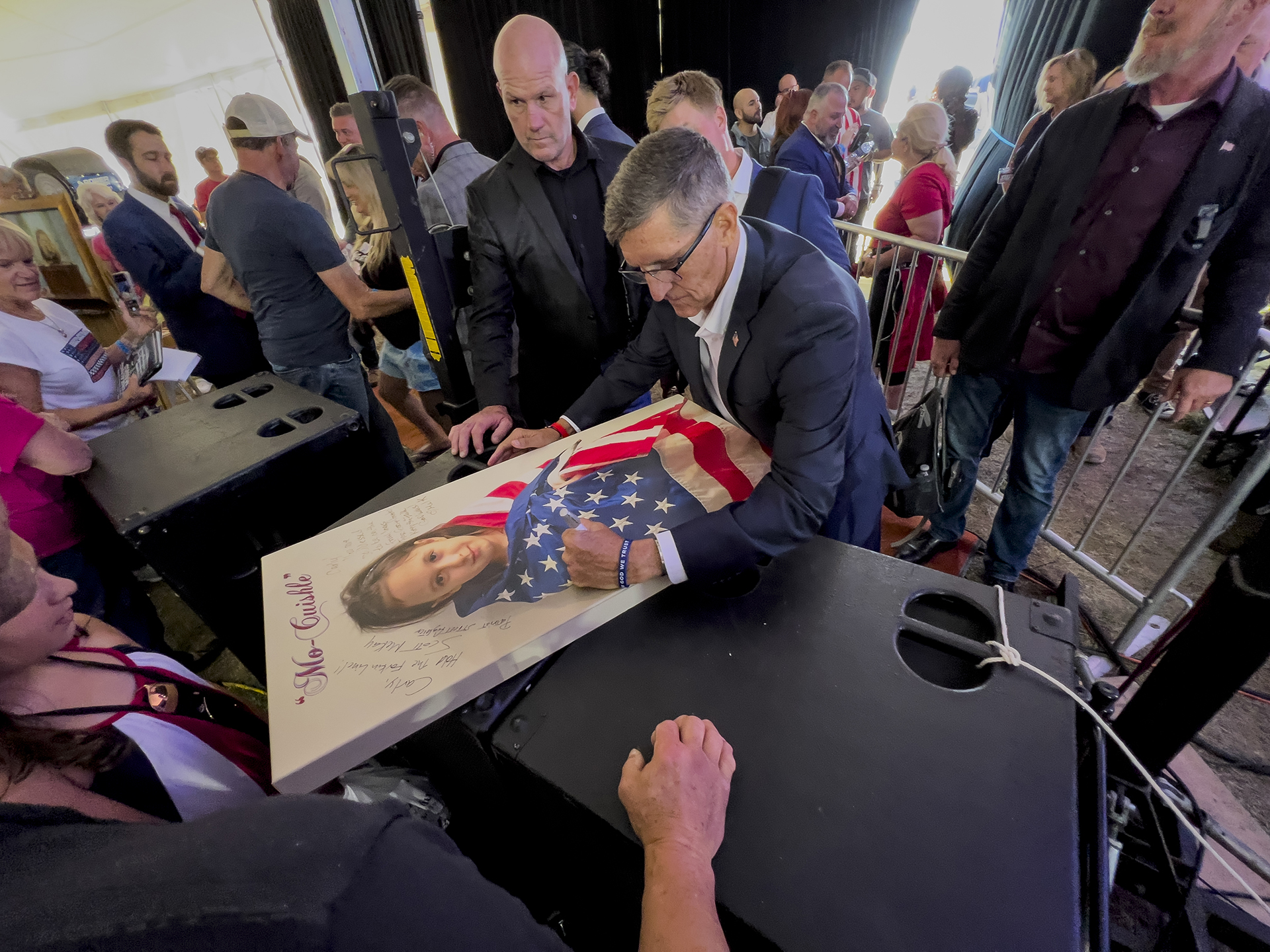 Michael Flynn, a retired three-star general who served as President Donald Trump’s national security advisor, autographs a picture of a girl wrapped in an American flag during the ReAwaken America tour at Cornerstone Church in Batavia, N.Y., Friday, Aug. 12, 2022. (AP Photo/Carolyn Kaster)