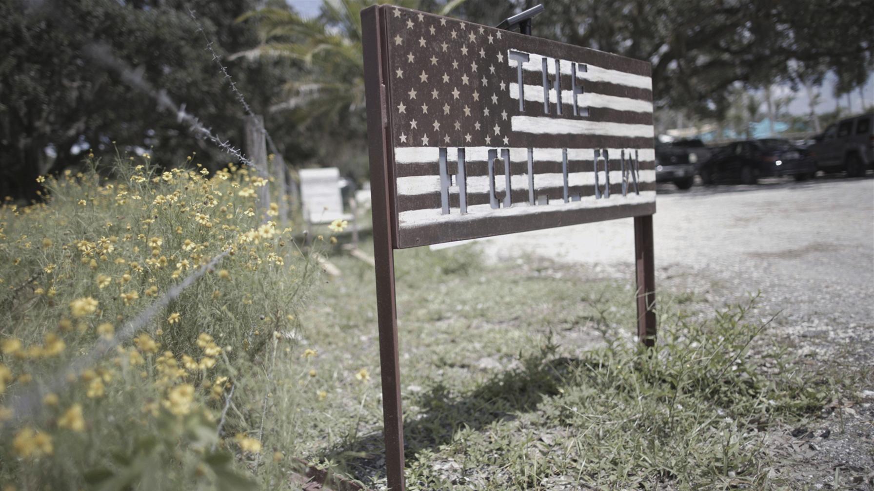 A sign for The Hollow, in the shape of a U.S. flag, stands in a parking lot at the venue in Venice, Fla., on July 31, 2022. After the failed Jan. 6, insurrection, retired three-star general Michael Flynn moved to Sarasota and set out to build a political community of like-minded people. He found an operating base of sorts at The Hollow, a 10-acre site that’s at times a children’s playland, wedding venue, organizing space and weapons training ground.