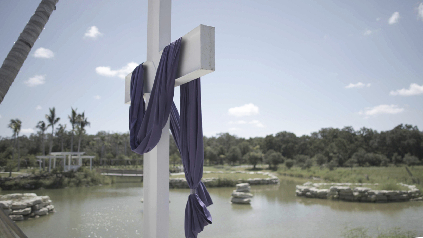 A cross stands near a pond at The Hollow, a 10-acre site in rural Venice, Fla., on July 31, 2022. Michael Flynn has been soliciting money for the venue through a crowdfunding campaign for The America Project, a group he started last year and that AP and Frontline previously reported has been spending millions on efforts to advance its agenda.