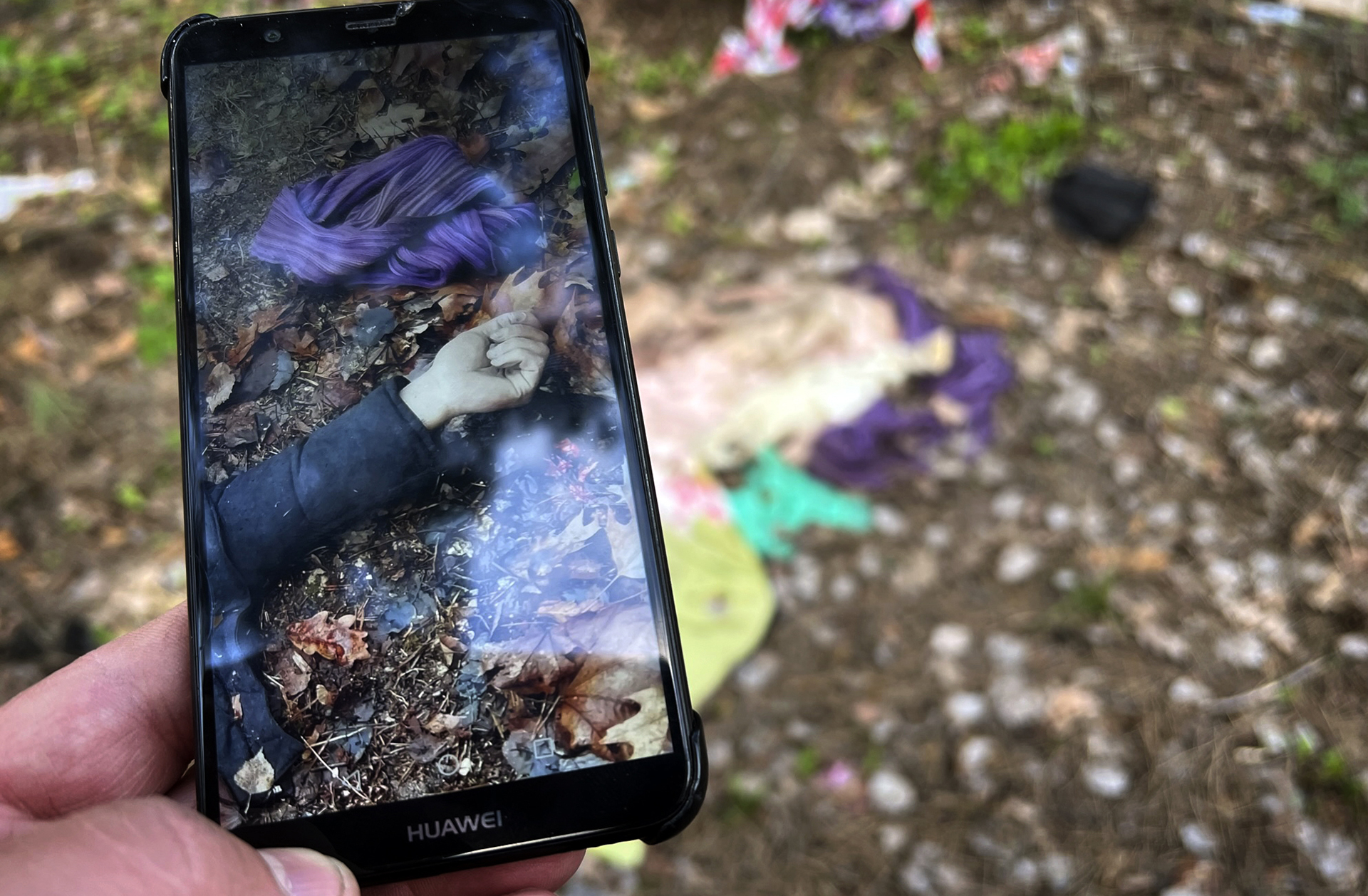 Father Vasyl Bentsa matches a photo he made when he discovered the bodies of five men tortured and killed by Russian troops in Zdvyzhivka, Ukraine, including Mykola "Kolia" Moroz, 47, with potential evidence of the crime left in the forest where the men were buried. (AP Photo/Erika Kinetz)