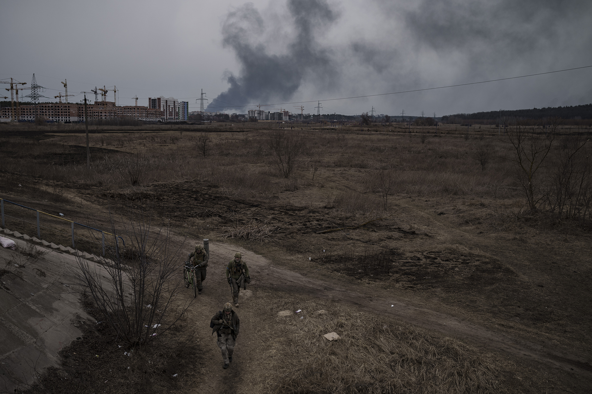 Soldiers walk on a path as smoke billows from the town of Irpin, on the outskirts of Kyiv, Ukraine, Saturday, March 12, 2022. The northwest suburbs of the capital, such as Irpin and Bucha had endured Russian shellfire and bombardment, prompting residents to leave their homes. (AP Photo/Felipe Dana, File)