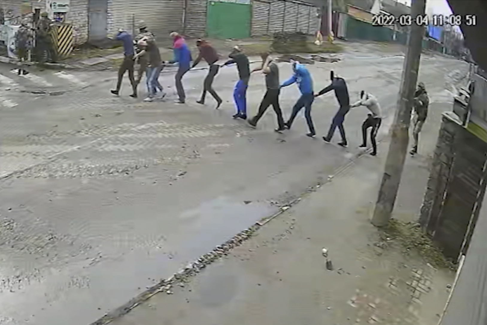 In this image from March 4, 2022, surveillance video obtained by the AP, Russian troops lead nine men at gunpoint to their headquarters on Yablunska Street in Bucha, where they would be tortured and executed. The men were picked up as part of what Russian soldiers called “zachistka” – cleansing. They hunted people on lists prepared by their intelligence services and went door to door to identify and neutralize potential threats. (AP Photo)