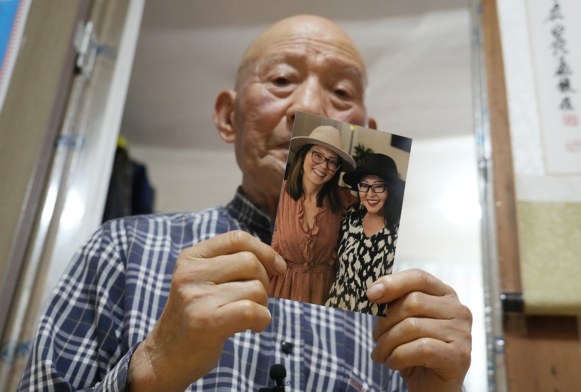Park Jong-kyun holds a photo showing his twin daughters, Dee Iraca, left, and Becca Webster, at his house on Jeju Island, South Korea, Wednesday, Feb. 21, 2024. His twins were born at a time when he and his late wife were struggling financially to raise three sons. His wife needed an emergency C-section, which the couple couldn't afford. The hospital persuaded them to give away the twins to relieve the financial burden and toll on his wife's health, Park says. (AP Photo/Ahn Young-joon)
