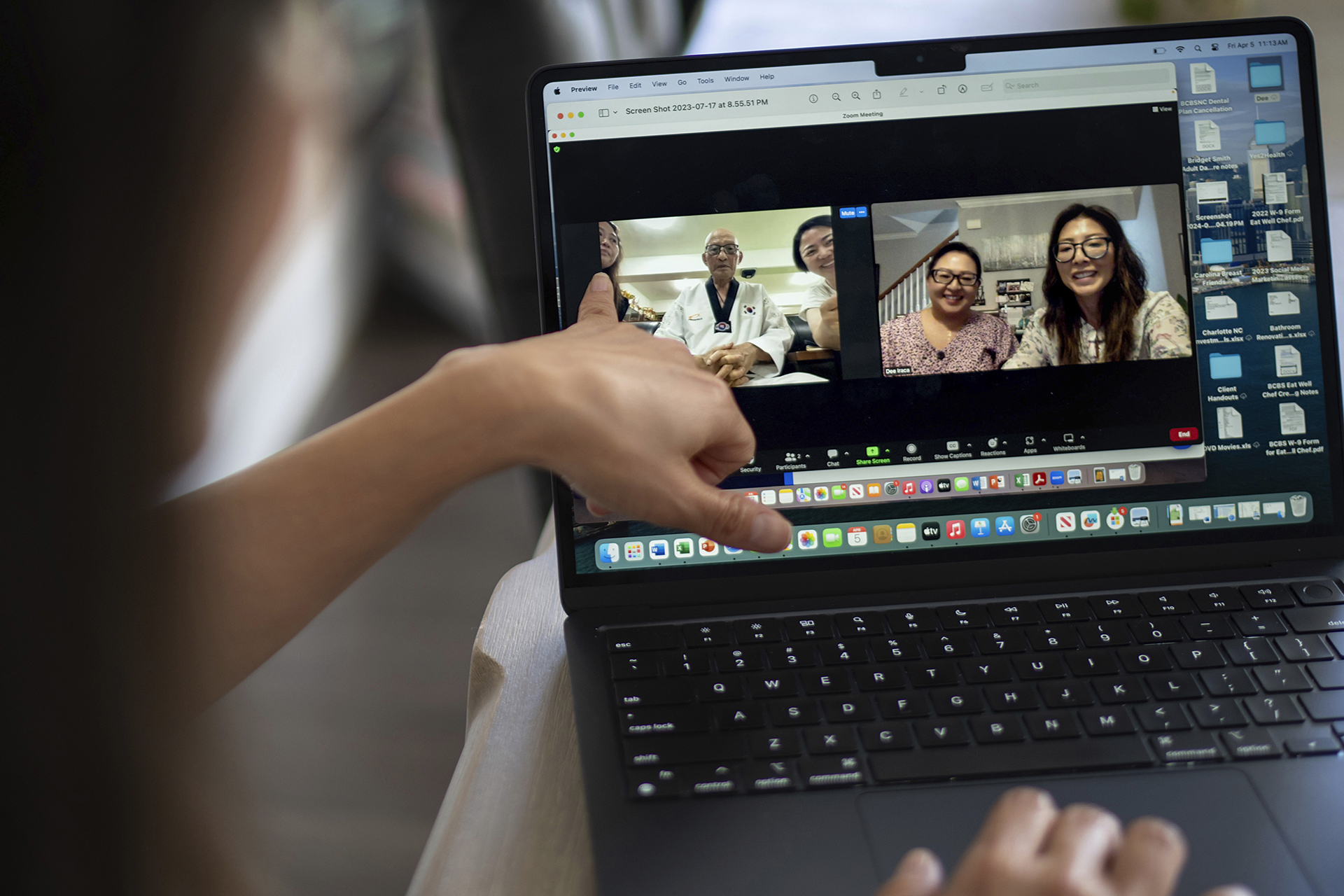 Dee Iraca, at her home in Davidson, N.C., on Friday, April 5, 2024, shows a video of a 2023 video call with her biological father, Park Jong-kyun. She points to fellow adoptee Rebecca Kimmel, left, who sat next to Park in South Korea as Iraca, seen in the window at far right, sits with her twin sister, Becca Webster, back in America. (AP Photo/David Goldman)