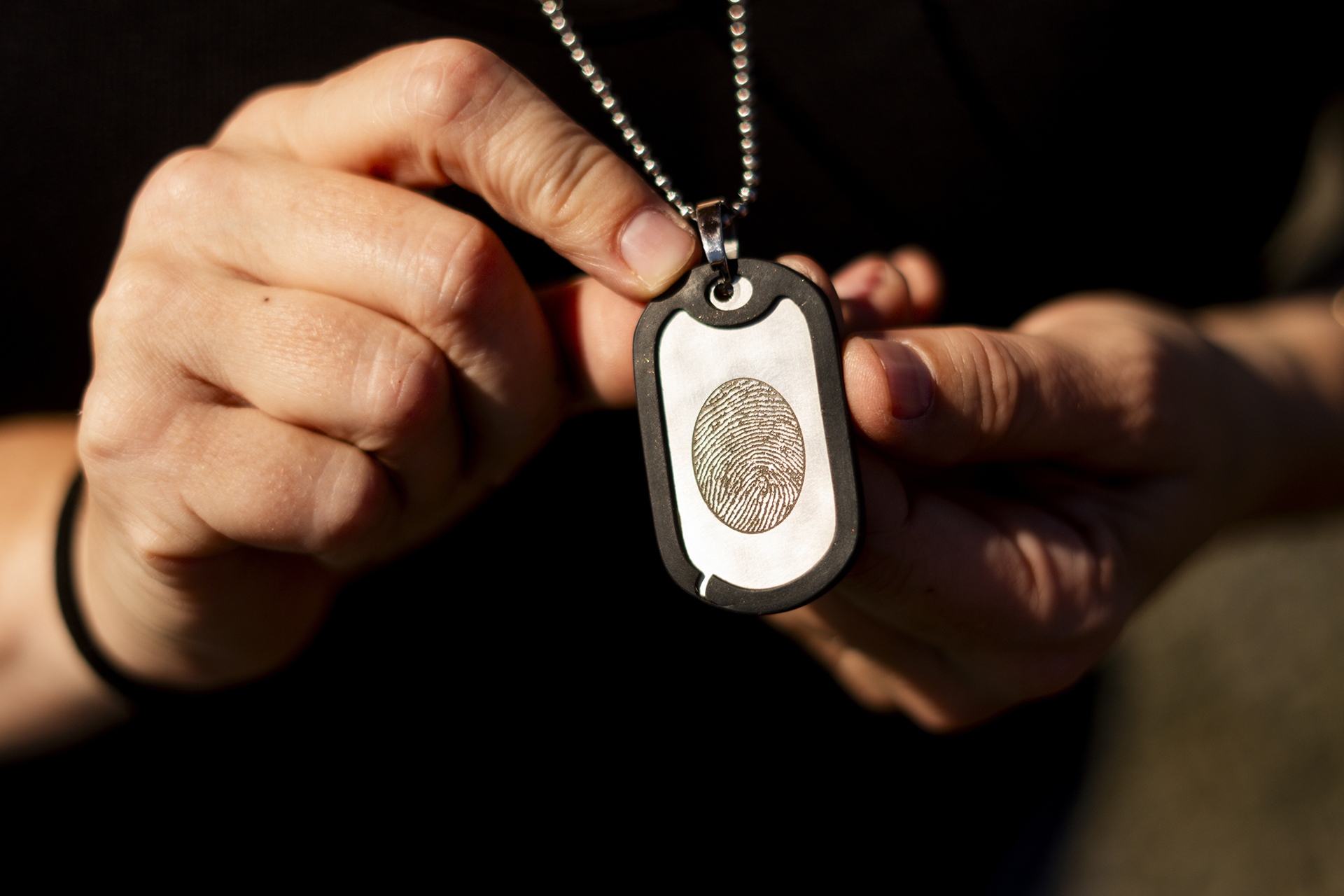 Jen Dold, whose brother, Alex Dold, lived with schizophrenia and died after a 2017 encounter with sheriff's deputies and police officers, holds a dog tag with her brother's fingerprint she wears around her neck Wednesday, Sept. 18, 2024, at a favorite beach of his in Edmonds, Wash. (AP Photo/Lindsey Wasson)