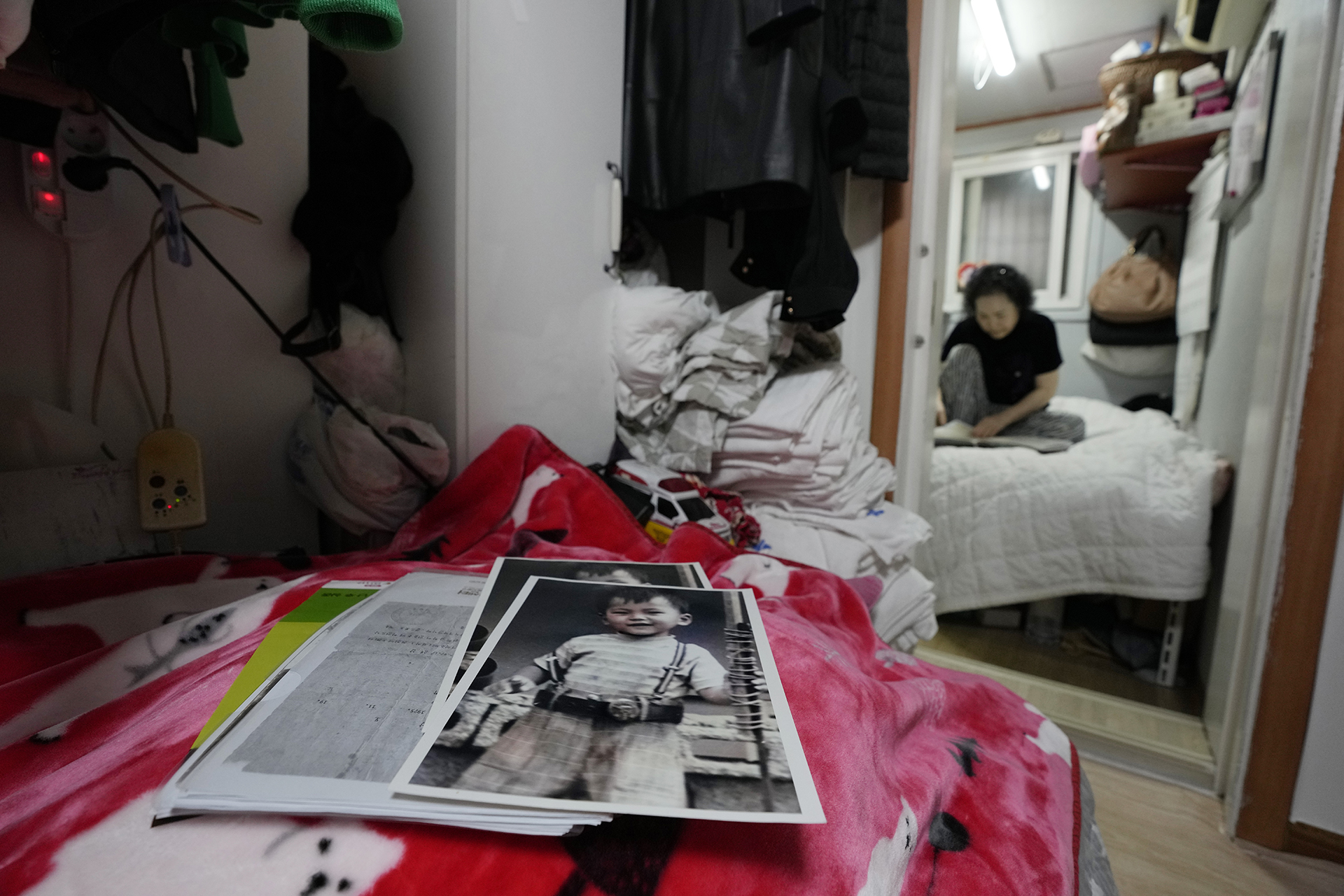 Photos of Choi Young-ja’s son, Paik Sang-yeol, who went missing in 1975, sit on a bed in her motel room in Seoul, South Korea, Tuesday, March 5, 2024. (AP Photo/Ahn Young-joon, File)
