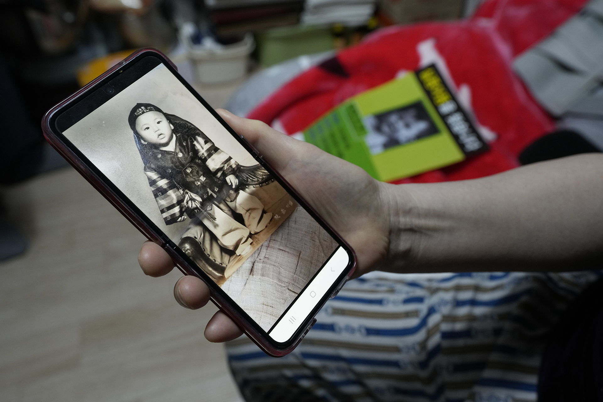 Choi Young-ja holds a smartphone displaying a photo of her son, who went missing in 1975, as she sits in her motel room in Seoul, South Korea, Tuesday, March 5, 2024.