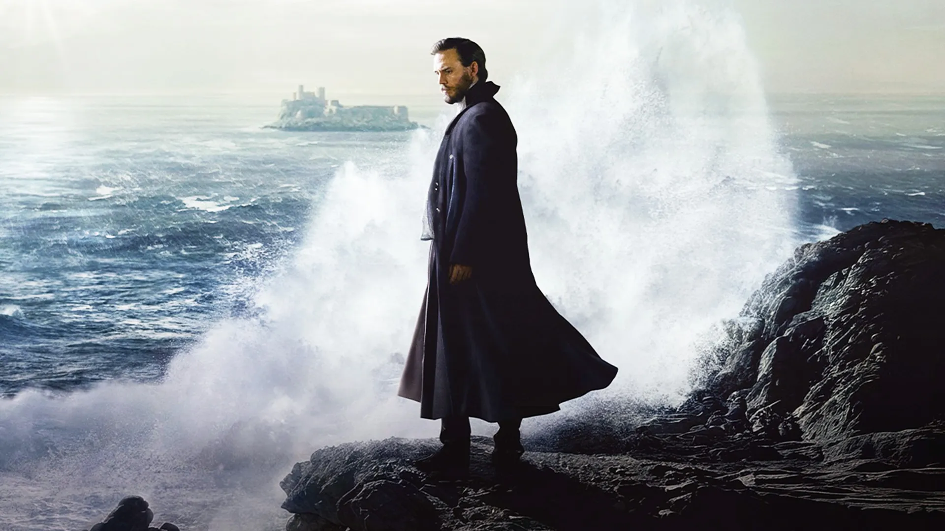 Image of a man in a cloak standing on a rocky ocean shoreline. It's the key art for the new adaptation of The Count of Monte Cristo, coming to MASTERPIECE on PBS.