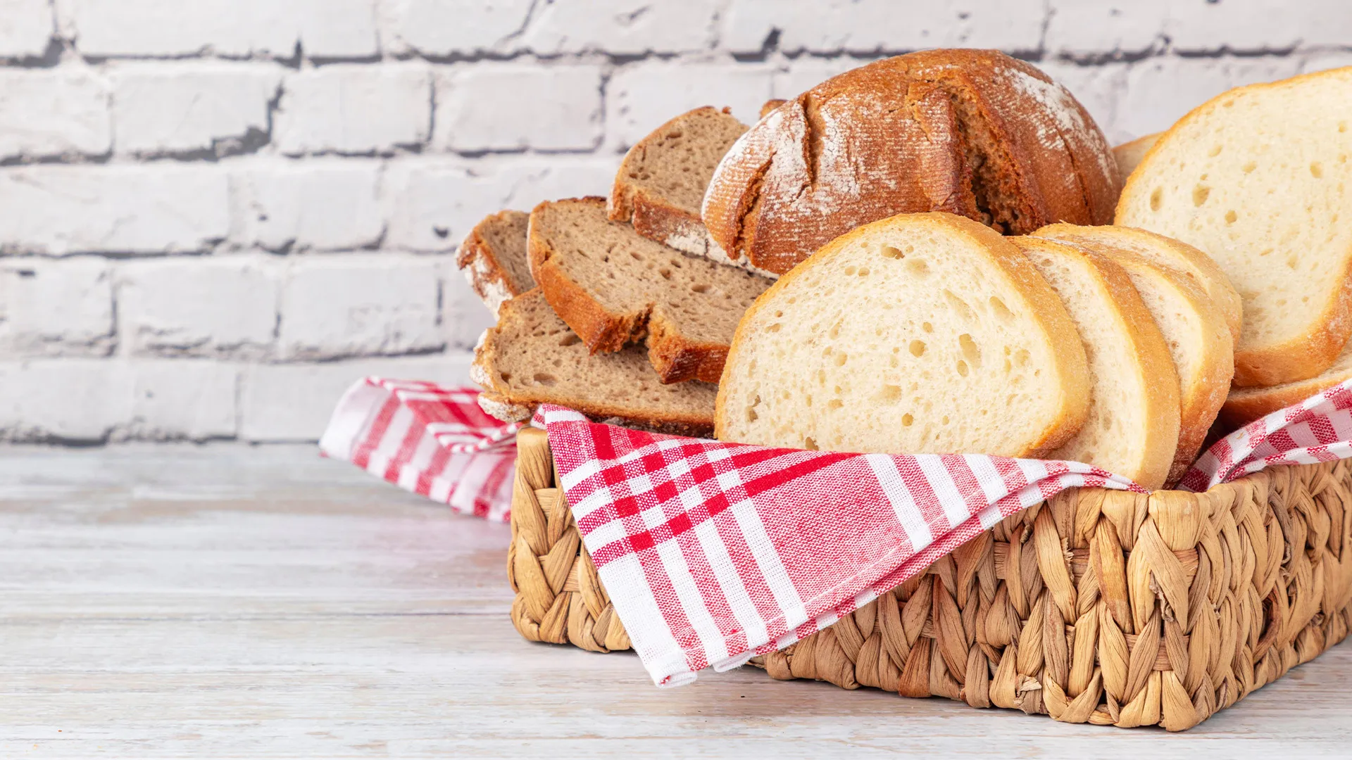Basket of sliced bread in front of a white brick wall.