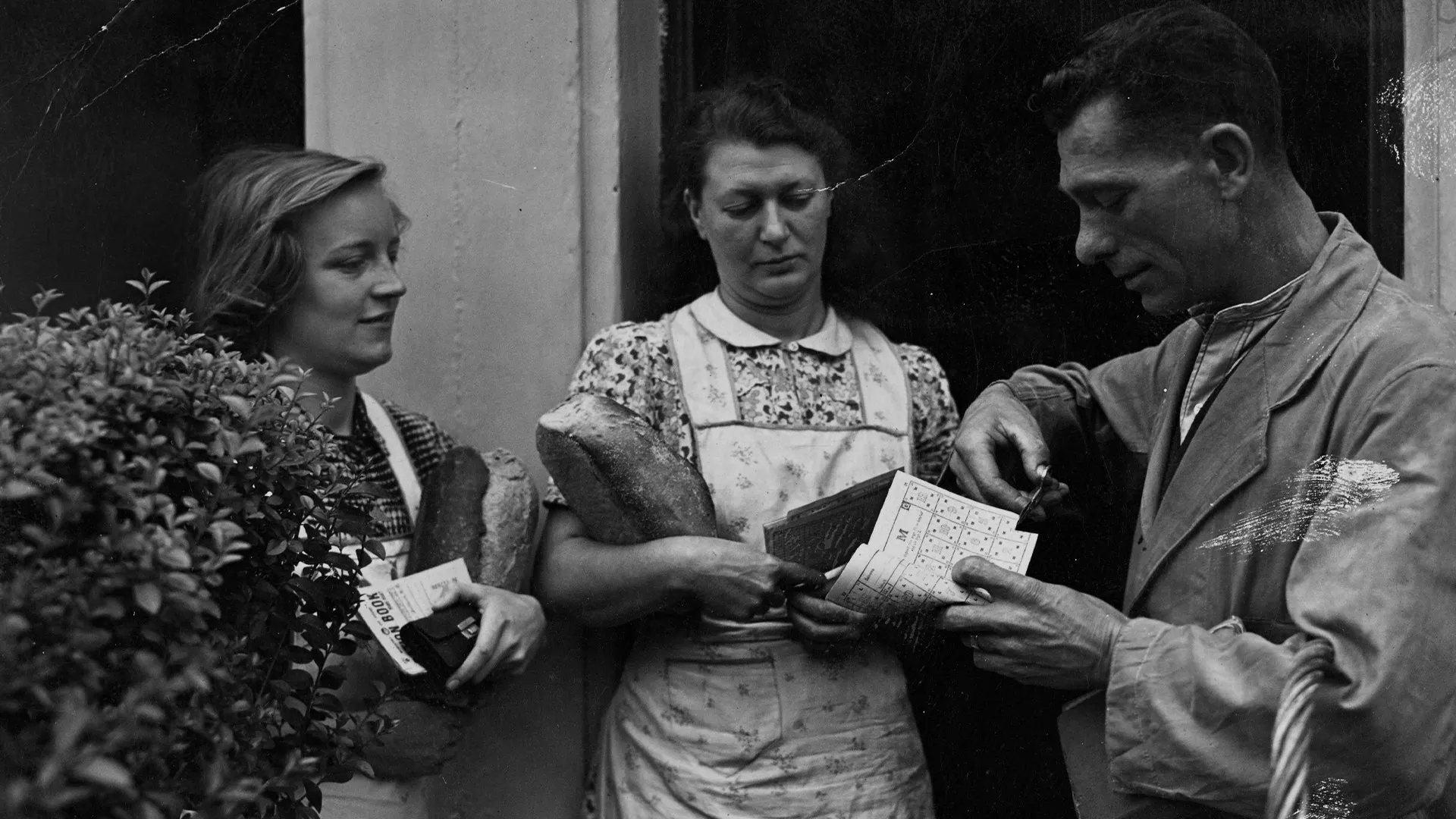 A baker's deliveryman cutting BU's (bread rationing units) from a customer's ration book at Stratford, London, 22 July 1946.