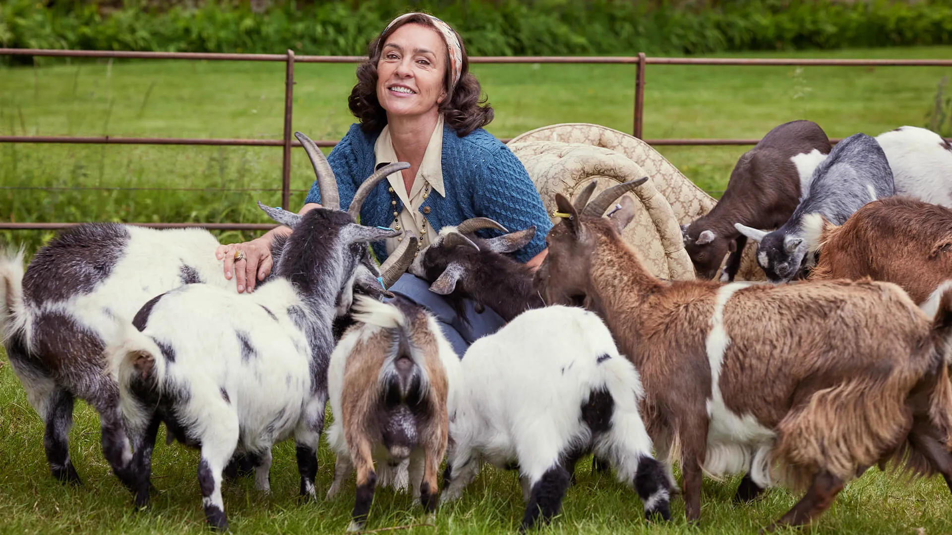 Actress Juliet Aubrey in costume as the character Miss Grantley, surrounded by her herd of pygmy goats in a scene from All Creatures Great and Small Season 5 on MASTERPIECE on PBS.