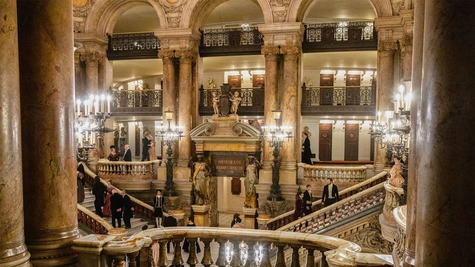 Candlelit interior of the magnificent Palais Garnier, home of the Paris opera, with marble statues, columns and ornate ingravings