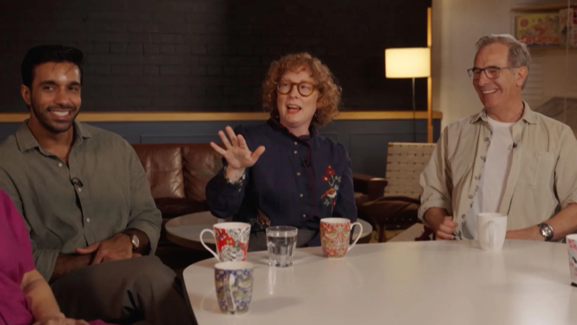Rishi Nair, Daisy Coulam, and Robson Green sitting around a table talking Grantchester Season 11