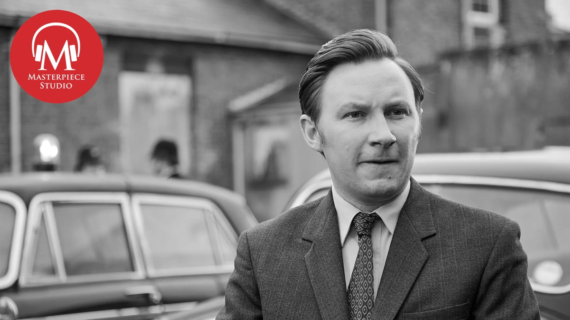 black and white photo of actor bradley hall as larry peters in grantchester with the red masterpiece studio logo in the top left corner