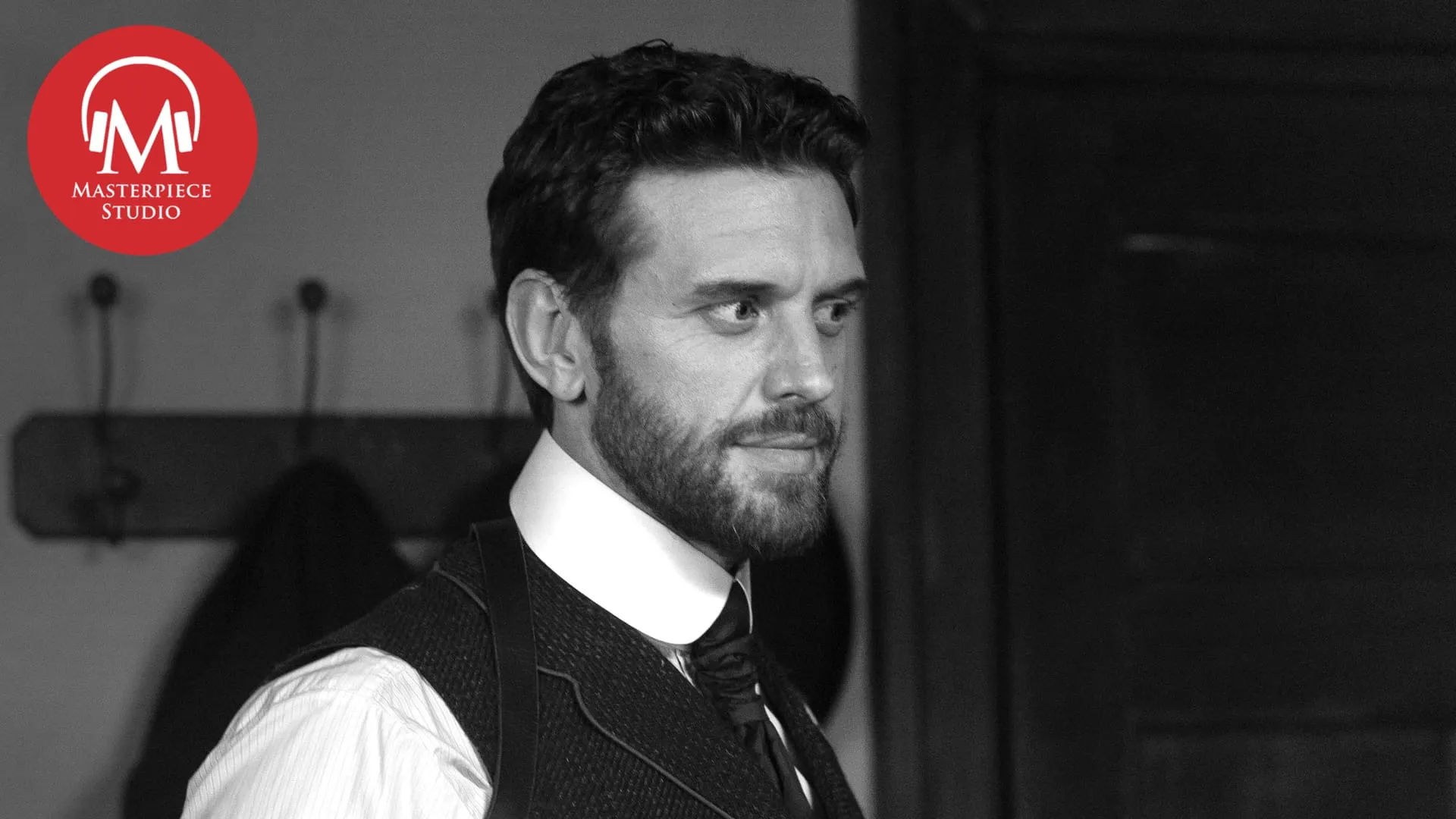 This is a black and white photo of actor Tom Durant-Pritchard from Miss Scarlet. He is looking to the right. The MASTERPIECE Studio red logo is in the top left