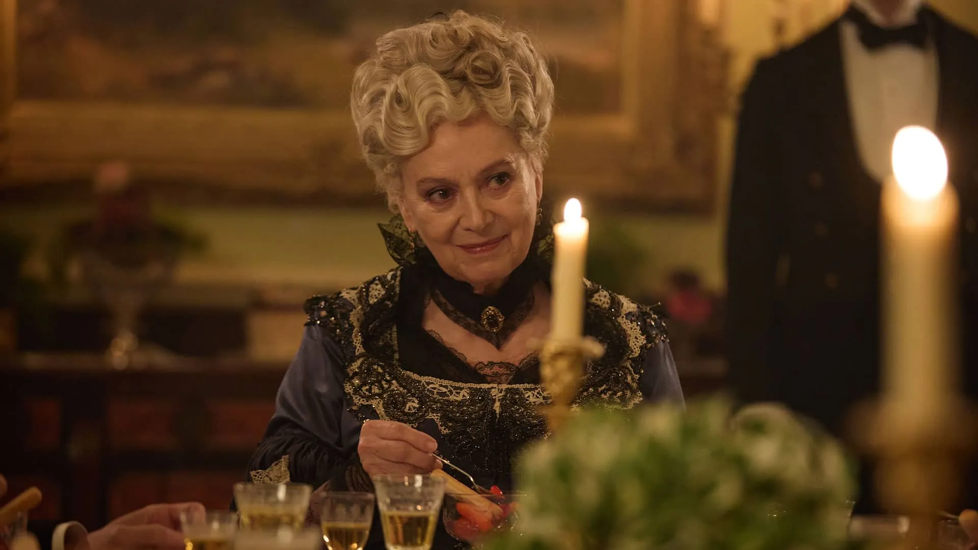 At a formal candlelit table, in formal Victorian clothes and with a knowing smile on her lips, sits Ann Forsyte