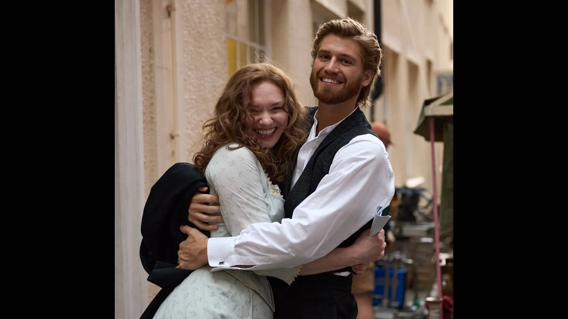 Actors Eleanor Tomlinson and Danny Griffin hug, laughing, on the set of The Forsytes