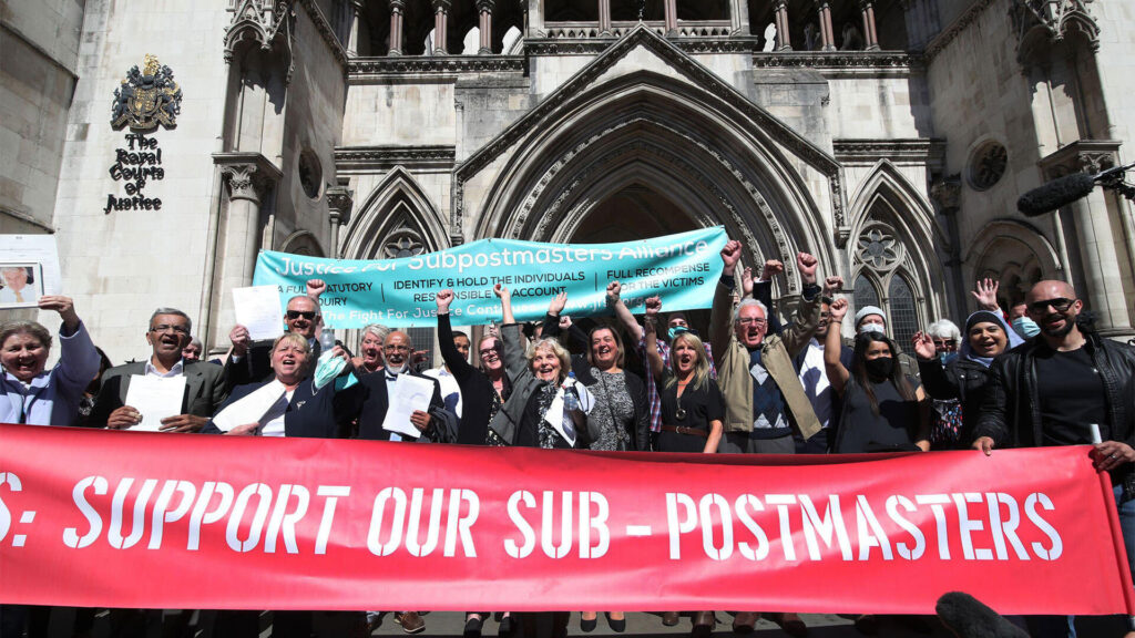 Scene outside UK High Court as British Subpostmasters win their group litigation case over the Post Office. Subpostmasters stand behind a red banner with arms raised.