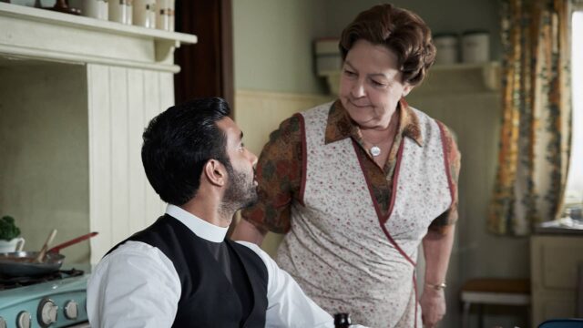 Rishi Nair as Alphy Kottaram and Tessa Peake-Jones as Mrs. C speaking in the kitchen in Grantchester Season 9