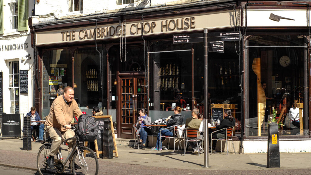 Color photo of the exterior of The Cambridge Chop House in Cambridge, England with outside diners and passersby.