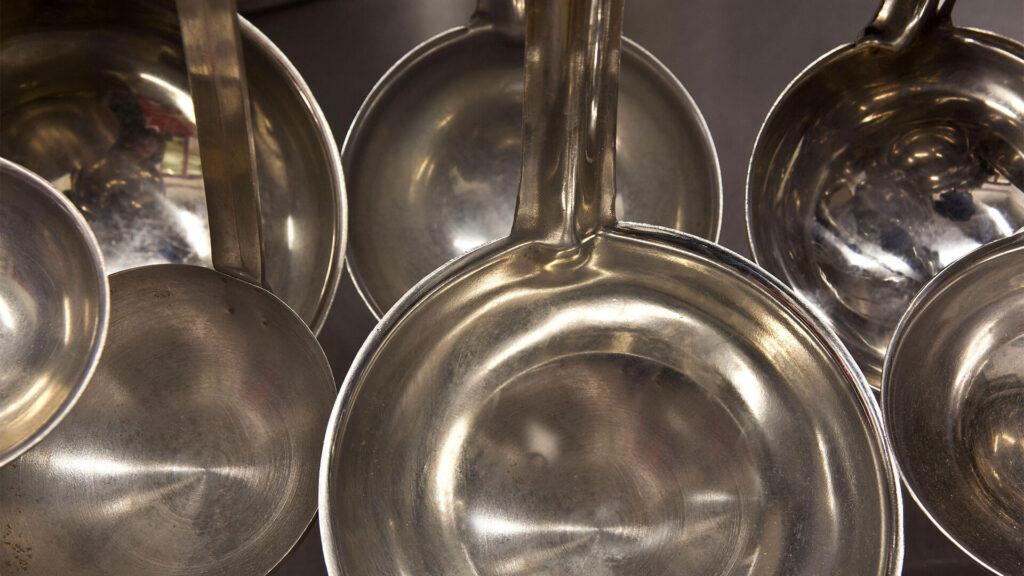 A close up photo of a cluster of stainless steel pots and pans.