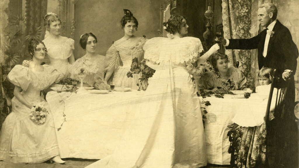 Antique black and white photo c1890 of Victorian wedding party with bridesmaids, bride and groom. Women dressed all in white as became the trend once Queen Victoria wore a white wedding gown.