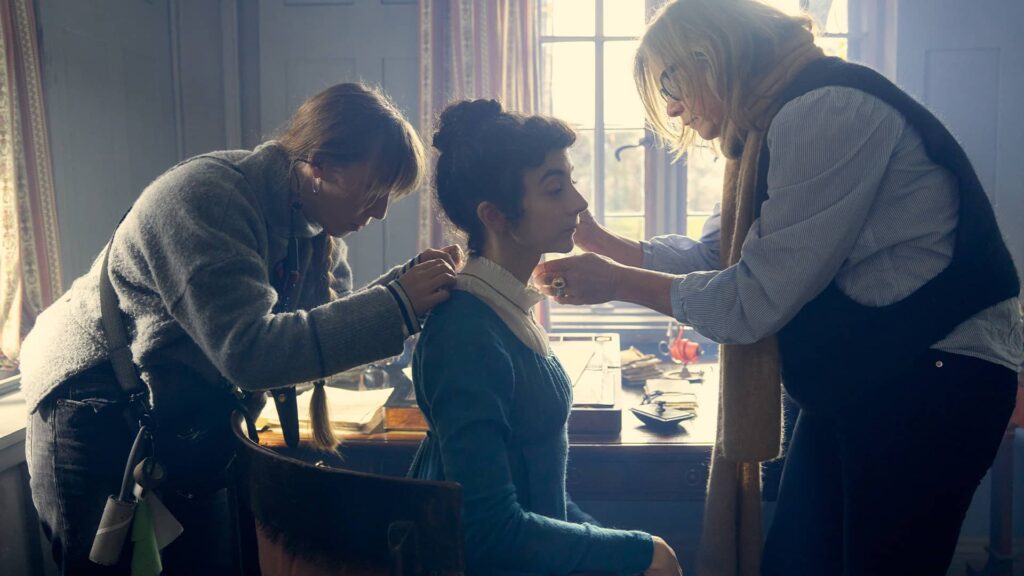 The crew give Patsy Ferran a touch up behind the scenes of Miss Austen