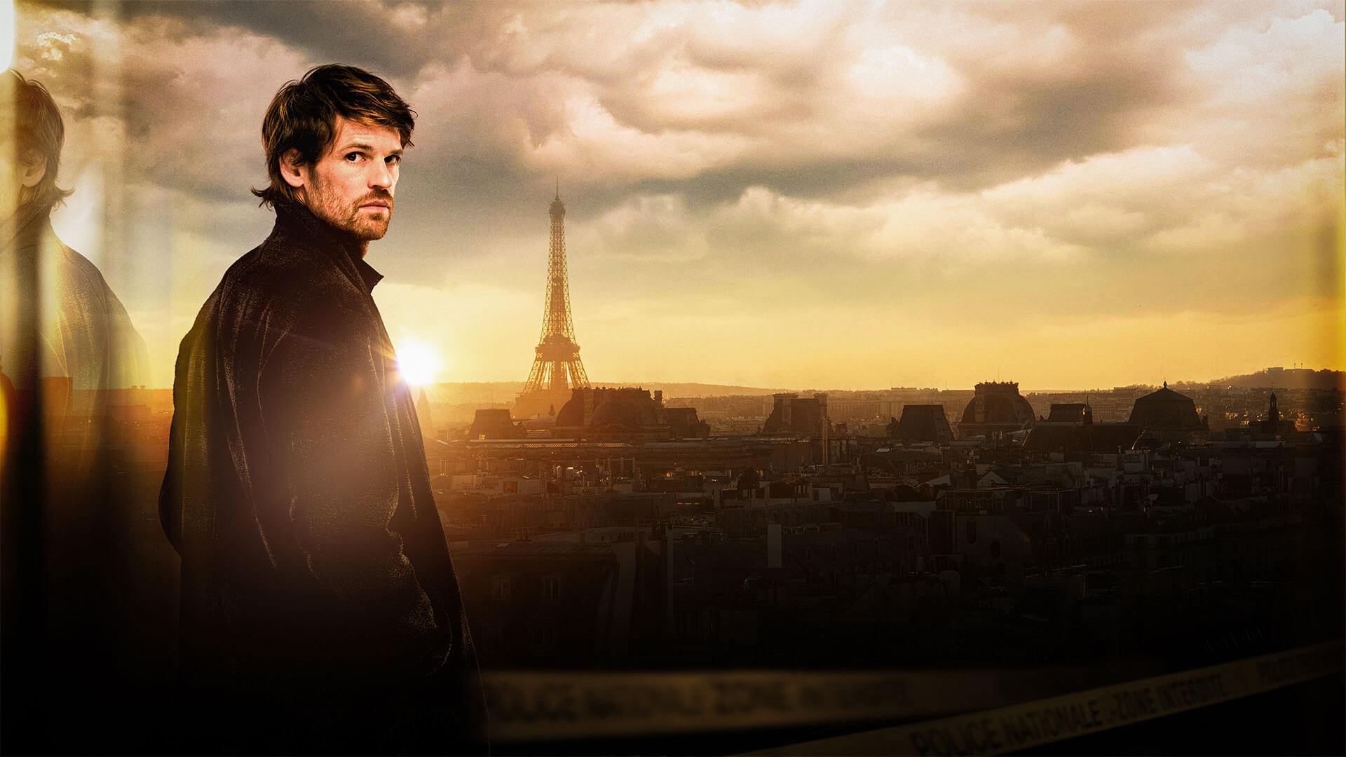 Actor Benjamin Wainwright in his starring role as Chief Inspector Maigret standing in front of a Paris skyline that includes the Eiffel Tower. PBS Masterpiece airs a new adaptation of Georges Simenon's detective stories called Maigret in 2025.
