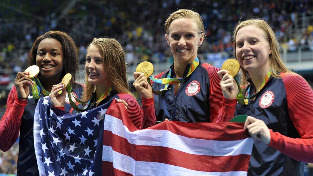 Photo from 2016 Olympics in Rio de Janeiro of USA's Kathleen Baker, Lilly King, Dana Vollmer, and Simone Manuel who gold medalled in the Women's 4x100 Medley Relay.