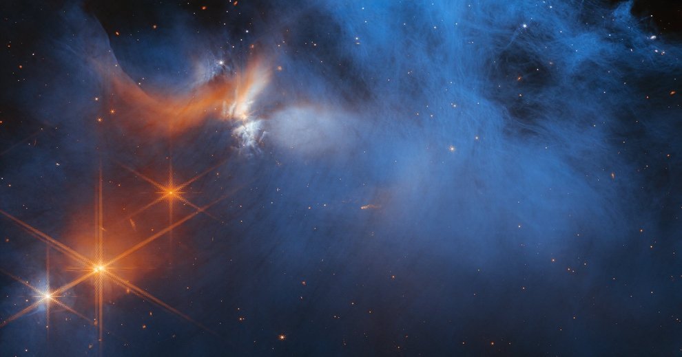 A gauzy pale blue cloud against the night sky, orange and white stars at the lower left