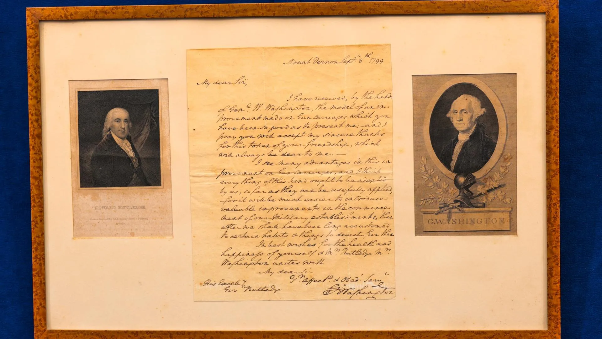 A Handwritten letter centered between two portraits placed in a wooden frame.