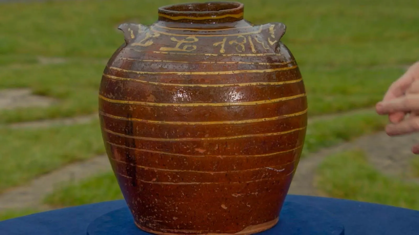 A red speckled jar with gold stripes and writing