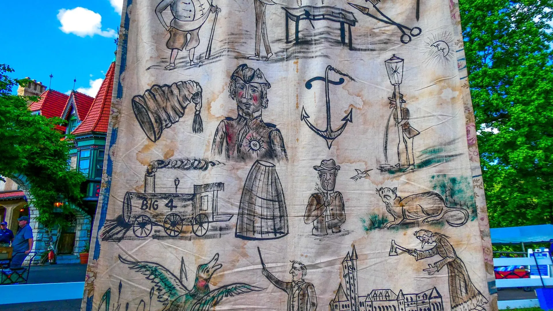 Close up on a weathered tapestry with drawings of different characters in black