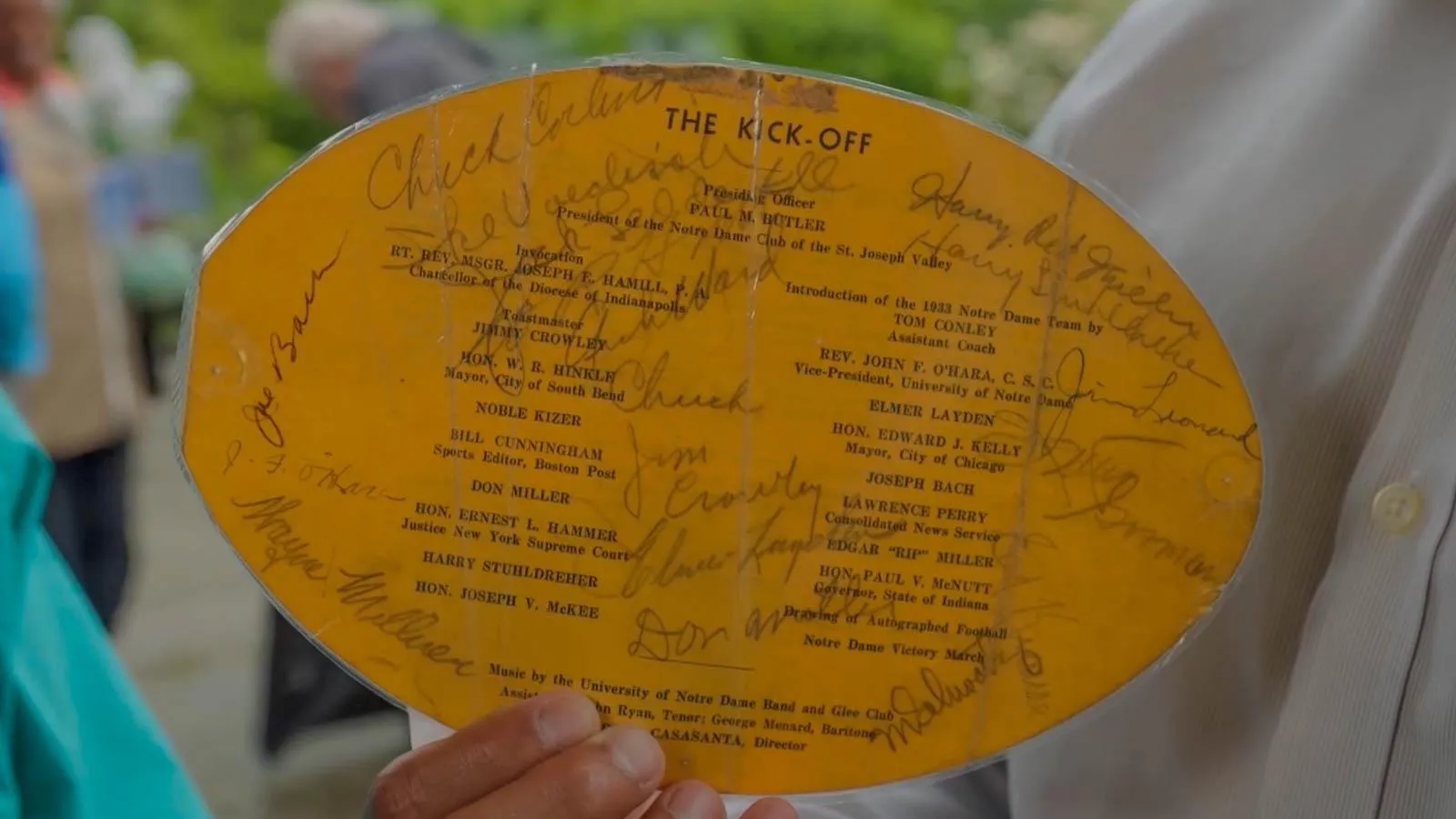 A yellow laminated football shaped program with various signatures.