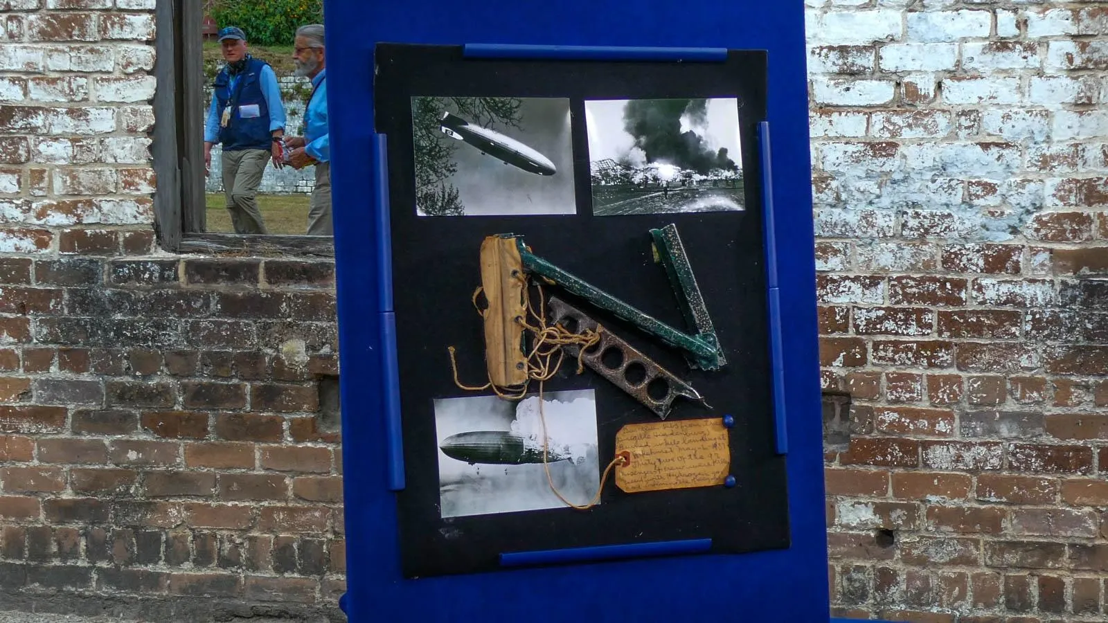 A shadow box of Hindenburg Airship Fragments fixed next to images of the Hindenburg Airship blowing up.