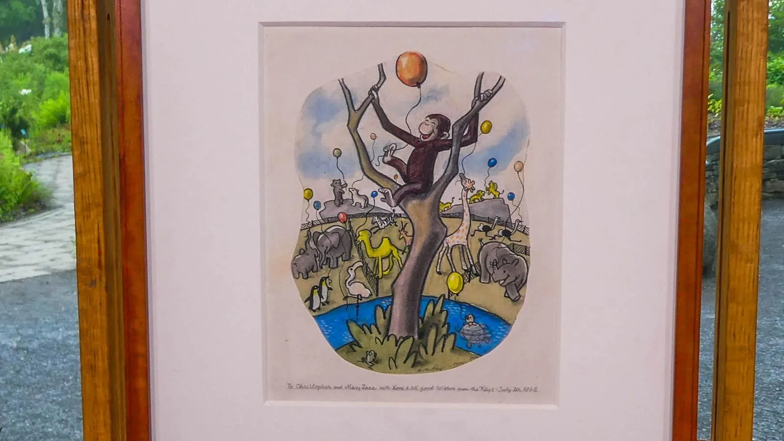 A framed picture of curiouse gerorge sitting in a tree holdin a balloon surrounded by other animals also with balloons.