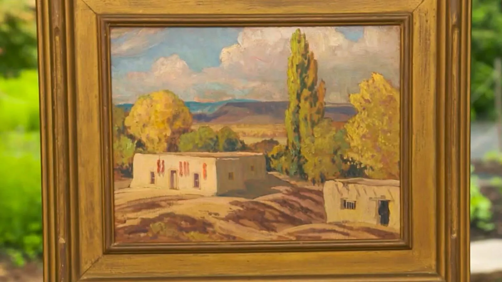 A landscape oil painting of a desert landscape centered on small white building in the left corner.