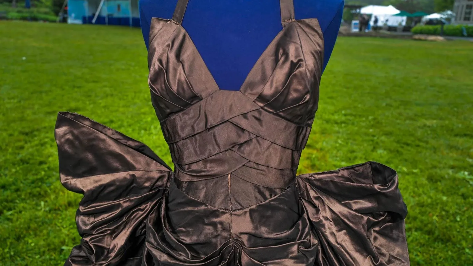 Close up of a black dress on a blue mannequin with criss cross detailing across the bodice.