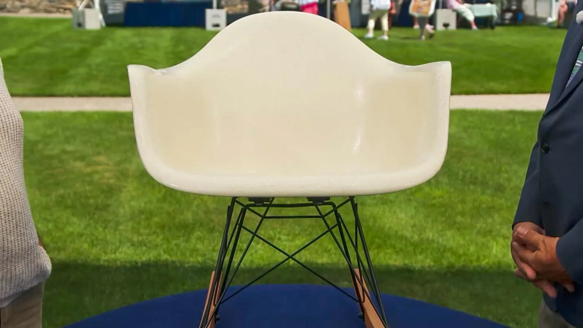 A cream chair with black wire legs sits on a display platform.